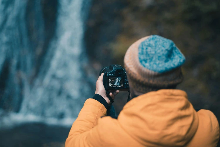 Photographer taking a wildlife photo of a waterfall in iceland.